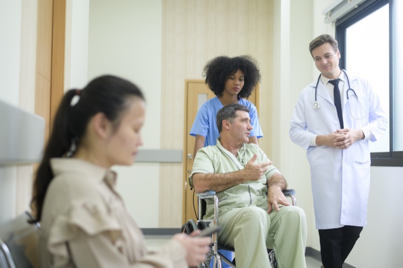 A doctor and nurse talking with a patient in a hospital corridor